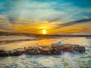 Sunset over arlands beach sea and rocks