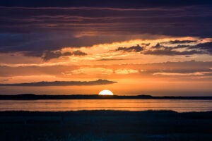 a golden sunset over keadue beach with a big sun
